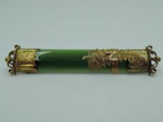 A New Zealand jade bar brooch having yellow metal decoration, no marks, tests as gold