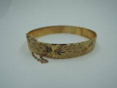 A 9ct gold hinged bangle having engraved star burst decoration and concealed clasp, approx 19.8g
