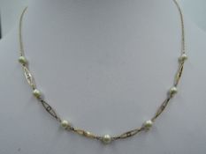A 9ct gold necklace having simulated pearls interspersed by decorative links on fixed chain,