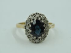 A sapphire and diamond chip oval cluster in a stepped claw mount to knife blade shoulders on a