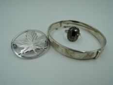 An HM silver hinged bangle having engraved foliate decoration, white metal kleaf brooch stamped