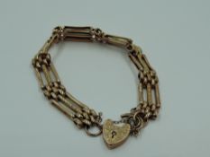 A rose gold three bar bracelet having an engraved padlock clasp stamped 9C (bracelet missing a bar),
