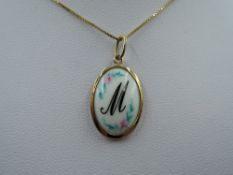 A ceramic pendant for initial M in a yellow metal mount on a 9ct gold box chain, approx 2.6g