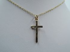 A 9ct gold cross pendant having engraved decoration on a yellow metal chain, approx 18' & 2.5g
