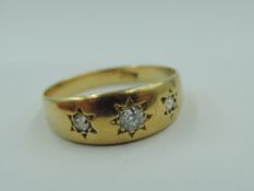 A Victorian yellow metal band ring stamped 18ct having three inset diamonds in star set mounts, size