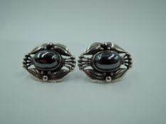 A pair of silver stud earrings by Georg Jensen having central hematite cabouchons in moulded open