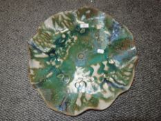 A large studio pottery platter using green and blue hues with raised leaf pattern.