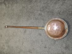 A traditional bed warming pan with copper warmer