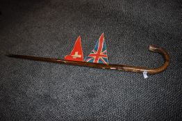 A vintage walking cane or pole having floral carving,flag and Switzerland sticker.