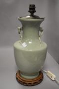 A pale green celadon glaze Chinese lamp with carved wooden base.