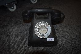A mid century black rotary telephone.