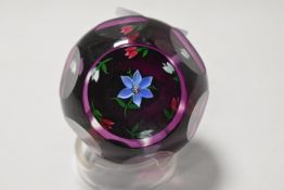 A Perthshire art glass paper weight having wheel cut windows through purple on lamp work floral