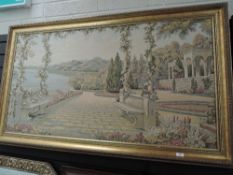 A framed machine woven tapestry showing classical scene with mountains and sea.