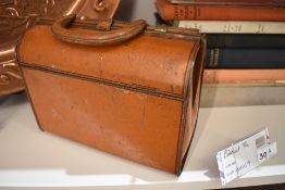 A vintage chocolate or biscuit tin in the form of a Gladstone bag.