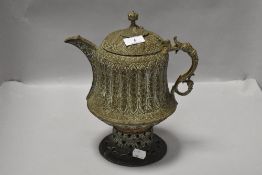 An Islamic/Persian embossed brass coffee pot with pierced circular base