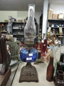 An antique oil lamp having blue glass reservoir and ornate cast base.