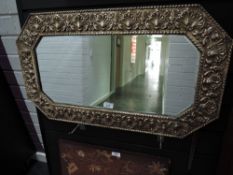 An antique embossed brass framed bevel glass mirror.