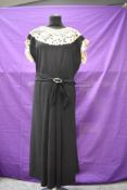 A black crepe 1930s dress having handmade lace to yolk and cuffs, side brass zip and half belted