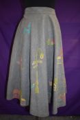 A 1950s grey cotton skirt having novelty embroideries of poodles, cottages, cars and more.