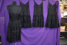 Four vintage black nylon slips having tiered underskirts, all are the same design, one still
