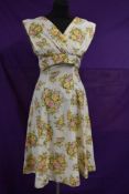 A vintage 1950s white cotton day dress with abstract rose pattern in yellow,pink,orange and green ,