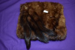 An early 20th century mink muff with tails and faux eyes, lined in chestnut silk, additional