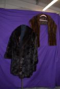 A dark brown mink coat and a lighter mink stole.