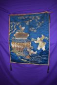 An antique oriental wall hanging using metallic and silk threads on blue silk.