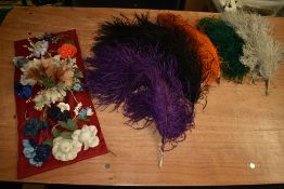 A striking selection of dyed ostrich feathers and a collection of fabric flowers,useful for