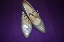 A pair of 1930s silver shoes having leather soles and button fastening to sides, one button