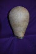 An early cloth covered wooden milliners head or wig stand with metal band incised with '54'.