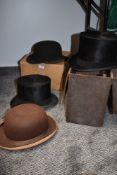 A collection of hats including top hat in box, brown bowler, black bowler and another black bowler