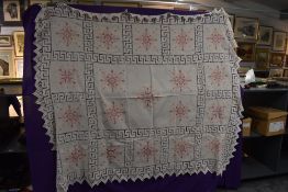 A large antique bed throw made up of panels of linen with crotchet panels between, cross stitch