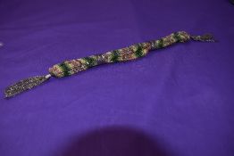 A late Georgian/early Victorian misers purse having original cut steel bands and colourful thread