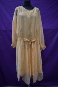 An early 20th century sheer apricot dress and a matching silk slip,with lace panel detailing to