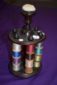 A late Victorian wooden cotton reel holder with pin cushion to centre of finial.