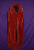A red velvet Victorian cape having gathered collar and hem.