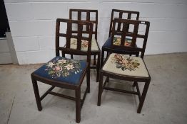 A set of four early 20th Century oak lattice back dining chairs having drop in woolwork seats