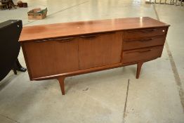 A vintage teak sideboard having three drawers and double cupboard on stylised legs, probably 1970s
