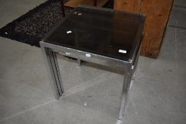 A vintage chrome nest of three tables with glass tops