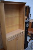 A modern beech finish full height bookcase having adjustable top shelves and cupboard under, w 84cm