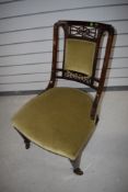 A Victorian nursing chair with mahogany frame and fretted back
