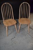 A pair of stripped Ercol style kitchen chairs having hoop and stick back and H stretcher