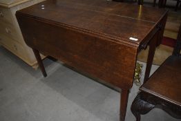 A 19th Century oak kitchen table having drop leaves and frieze drawer
