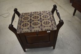 An early 20th Century mahogany stool with drop front compartment for music