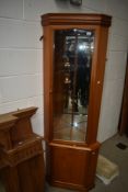 A modern corner display in teak with mirror back and glass shelves to top section, cupboard under