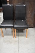 A pair of modern dark brown leather effect dining chairs on wood legs
