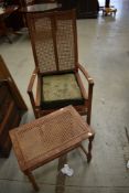 An early 20th Century golden oak and canework armchair and footstool
