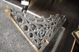 A pair of heavy vintage cast iron brackets having ornate detailing.