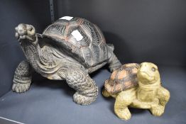 A modern cast-resinous model of a tortoise, sold together with a smaller tortoise form money bank